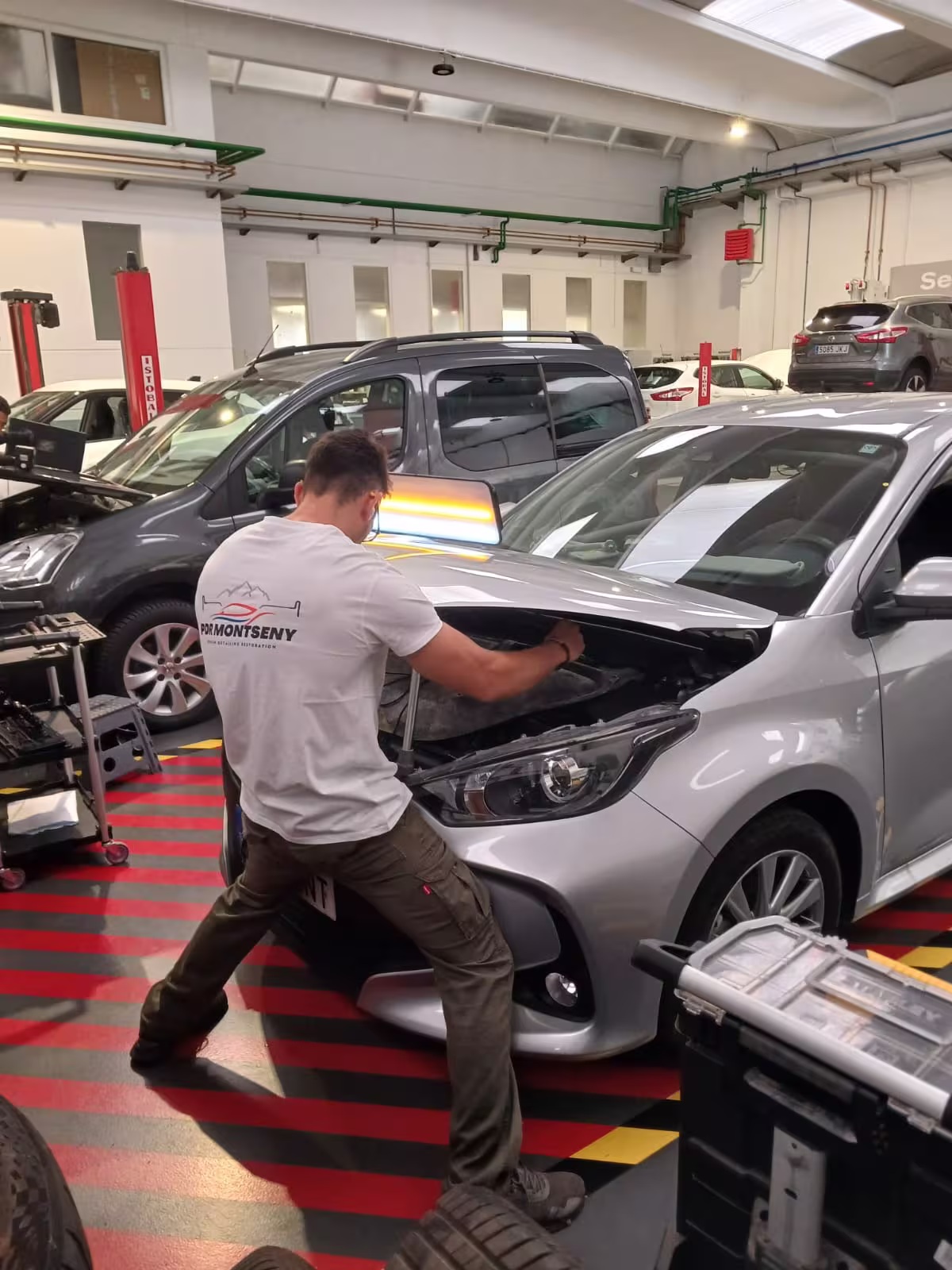 Técnico de producción trabajando sobre frontal de vehículo